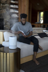 doTERRA difuzorius naudojamas namuose o šone juodaodis vyras skaito knygą